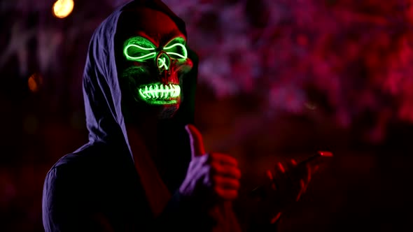 Portrait of a Person in a Terrible Glowing Mask of Death and in a Hood Against a Background of