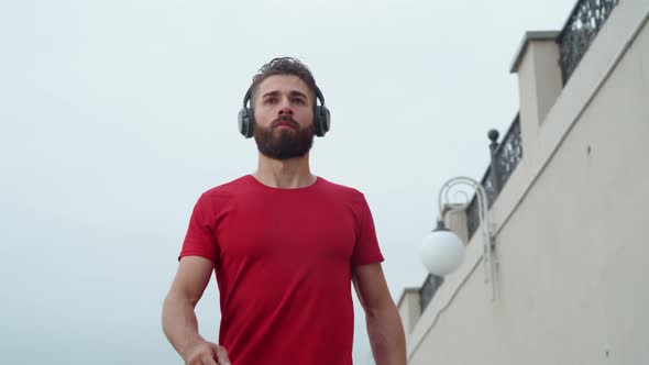 Man in an Athlete in Red Is Jogging in an Urban Environment