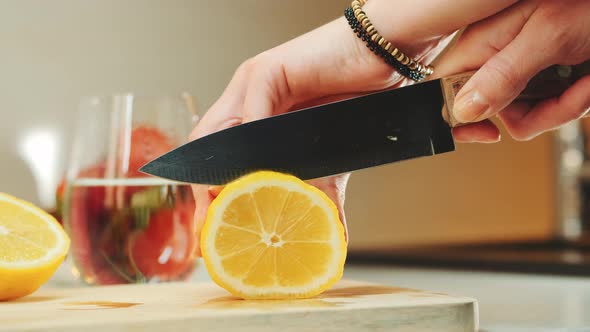 Close Up of She Cutting Off a Slice of Lemon on Wooden Kitchen Board