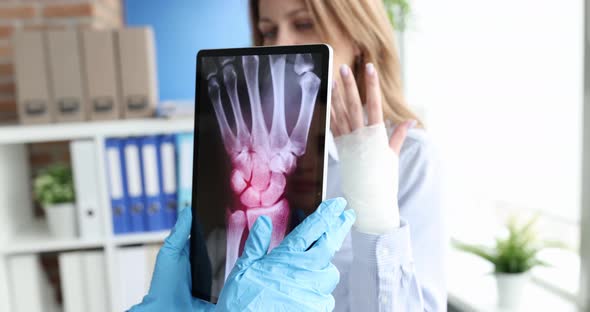 Doctor Holds Tablet with Xray of the Hand of Patient with Pain in Wrist Joint