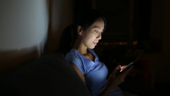 Woman using digital tablet at night