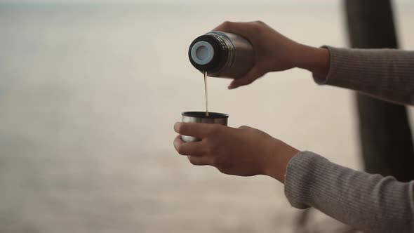 Woman Pouring Coffee Into Cup. Hot Tea From Thermos. Holiday Vacation Trip And Relaxing Moment.