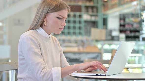 Young Woman Angry on Laptop in Cafe