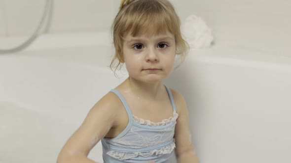 Cute Blonde Girl Takes a Bath in Swimwear. Little Child, 4 Years Old. Hygiene
