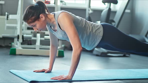 Young Woman Doing Pushups on Exercise Mat at Gym