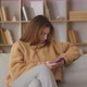 Happy Young Woman Relaxing on Cozy Couch Using Smartphone - VideoHive Item for Sale