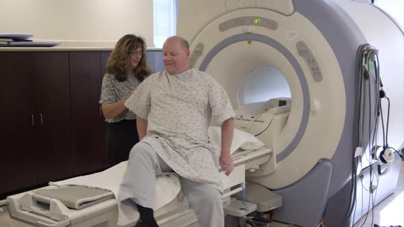 Man climbing onto MRI scanning table.