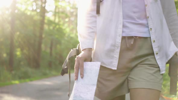A Tourist Girl Holds A Travel Map With Her Hand, A Tourist Walks With A Map Hiking A Girl Walks