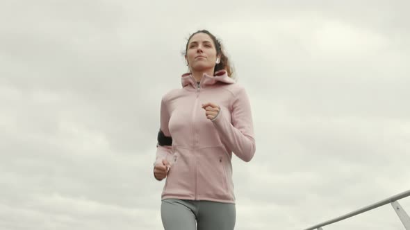 Slim Woman Running along Embankment