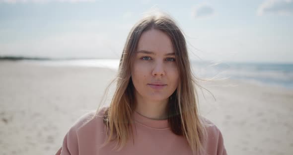 Close Up Portrait of a Young Woman Standing on a Beach Looking at Camera Smiling