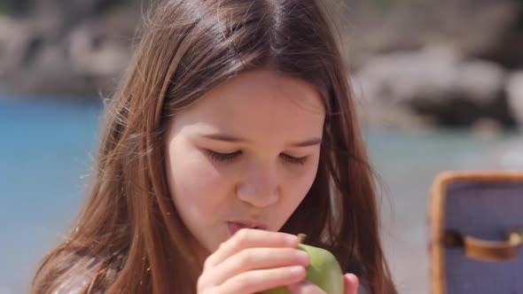 Girl eating apple on Family picnic near sea on sunny summer day.