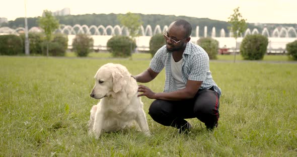 Black Man Stroking His Dog in the Park