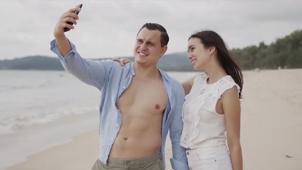 Pleased People in Love Making Selfie on Smartphone and Smiling at Exotic Ocean Side