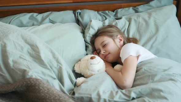 Girl with Teddy Bear in Bed