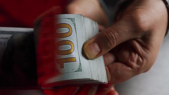 Hands Checks US Dollar Bills or Counting in Cash Against the Backdrop of Police Car Lights