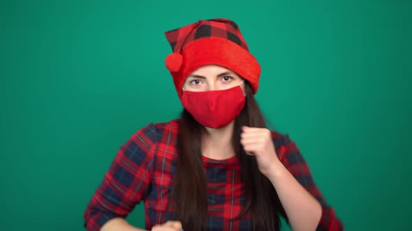 Young Cheerful Woman Wearing Red Medical Mask in Christmas Santa Hat Dancing