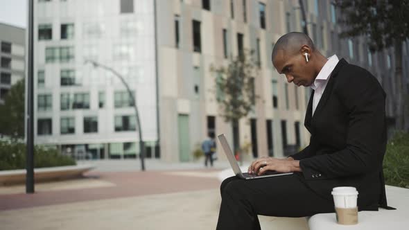 Concentrated African businessman working on laptop in headphones