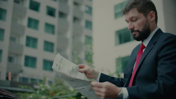 Senior Middleaged in an Expensive Suit with a Beautiful Beard in Black Blue Jacket Sits on Bench in