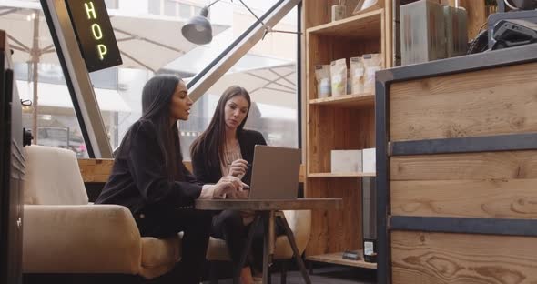 Two Women Sitting and Working in a Modern and Industrial Style Cafe