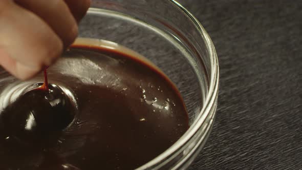 Closeup Hand Immersing Cherry in Hot Chocolate in Slow Motion