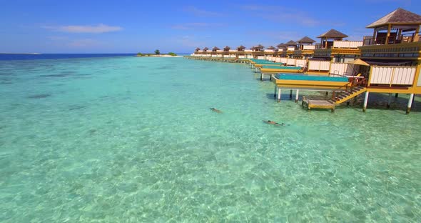 Aerial drone view of a man and woman couple with seascooters snorkeling near overwater bungalows