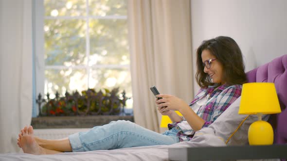 Woman Using Phone Sitting In Bed At Home Relaxing On Weekend.