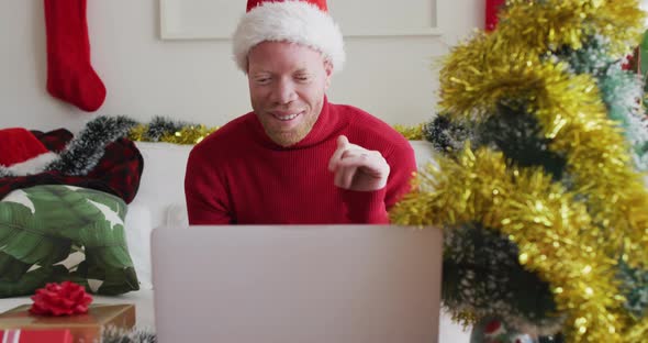 Happy albino african american man wearing santa hat making video call at christmas