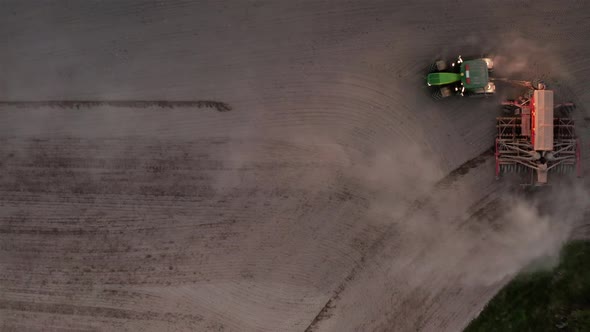 AERIAL - Tractor turns around sowing seeds at dusk, Dalarna, Sweden, plan view