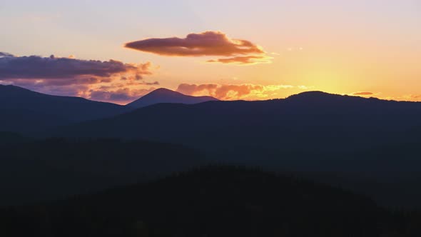 Beautiful Evening Panoramic Landscape with Bright Setting Sun Over Distant Mountain Peaks at Sunset