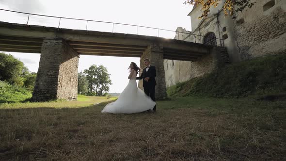 Groom with Bride Dancing Near Old Castle Bridge. Wedding Couple. Newlyweds