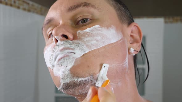 Male Shaving with Razor White Wall Background