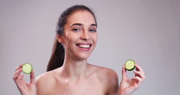 Girl Hiding Eyes Behind Cucumber Slices 