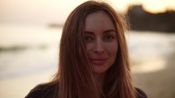 Portrait of a Blonde Girl Standing on the Beach in Autumn and Smiling