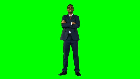 Businessman standing with arms crossed against green background