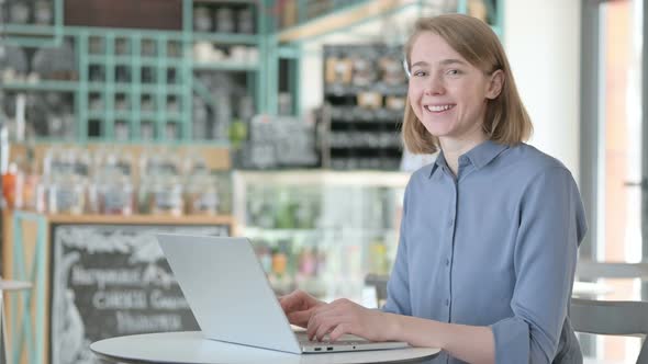 Young Woman with Laptop Showing Thumbs Up Sign