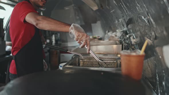 Young Man Making Hot Dogs at Food Trailer