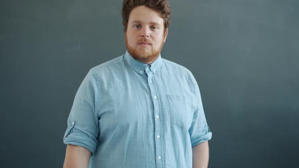 Portrait of Confident Young Man Looking at Camera Then Putting on Trendy Sun Glasses on Gray Color