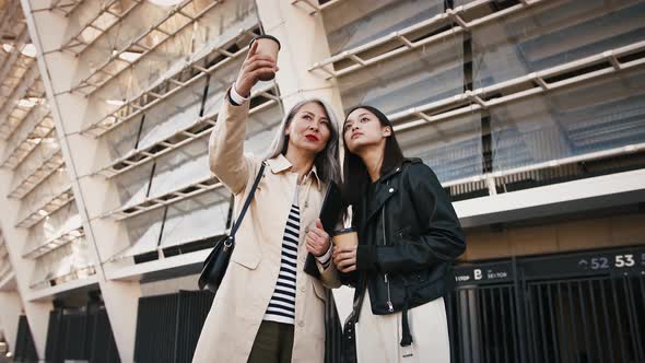 Asian Middleaged Lady is Holding Folder and Paper Cup of Coffee Discussing Business Plans with