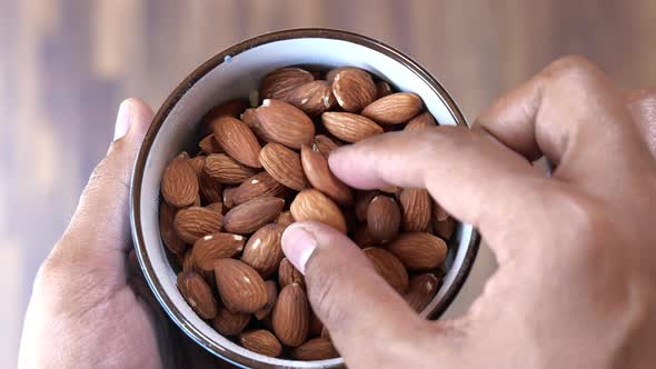 Top View of Man Hand Picking Almond From a Bowl 