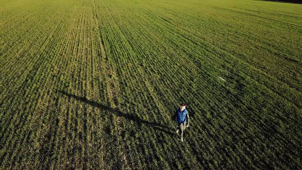 Boy running on the green field towards the moving camera and looking into it