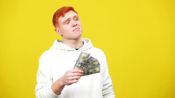 Young Redhead Man Using Cash As Fan Looking at Camera with Egoistic Facial Expression