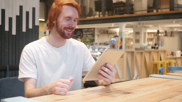 Online Video Chat By Redhead Beard Man on Tablet PC in Cafe