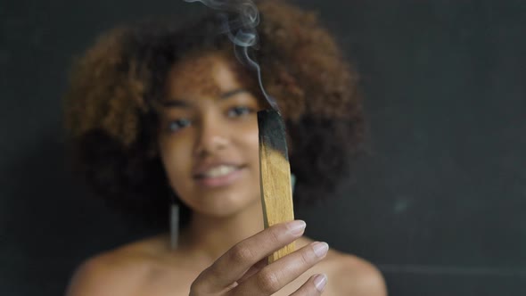 Mixed Race Woman Burns Palo Santo Wood Stick Spreading Smoke