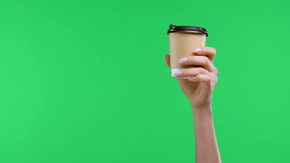 A Woman's Hand Holds a Paper Cup of Coffee with the Other Hand Points the Index Finger at the Coffee