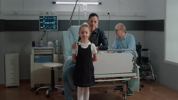 Portrait of Child and Mother Visiting Old Patient in Hospital Ward Bed