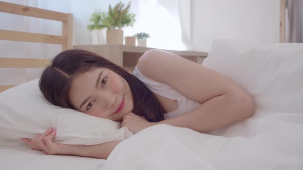 Asian woman smiling lying on bed in bedroom, Beautiful japanese using relax time after wake up.