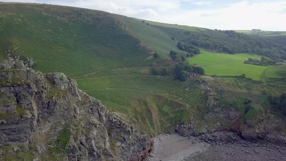 Forward tracking aerial of Wringcliff Bay near the Valley of Rocks. Amazing summer green colours of