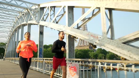 A couple running across a bridge with the Eiffel Tower