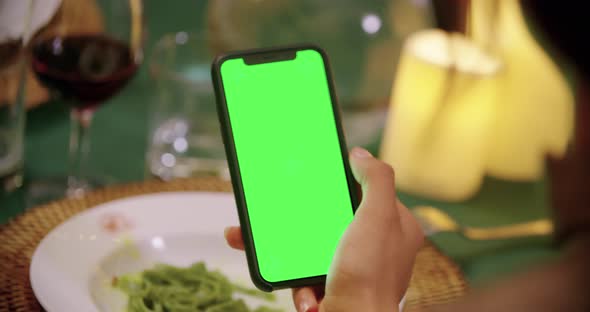 Woman Using Green Screen Smartphone Device During Elegant Gourmet Night Dinner. Friends Italian Trip