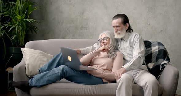 Senior Couple Sitting on Couch with Laptop